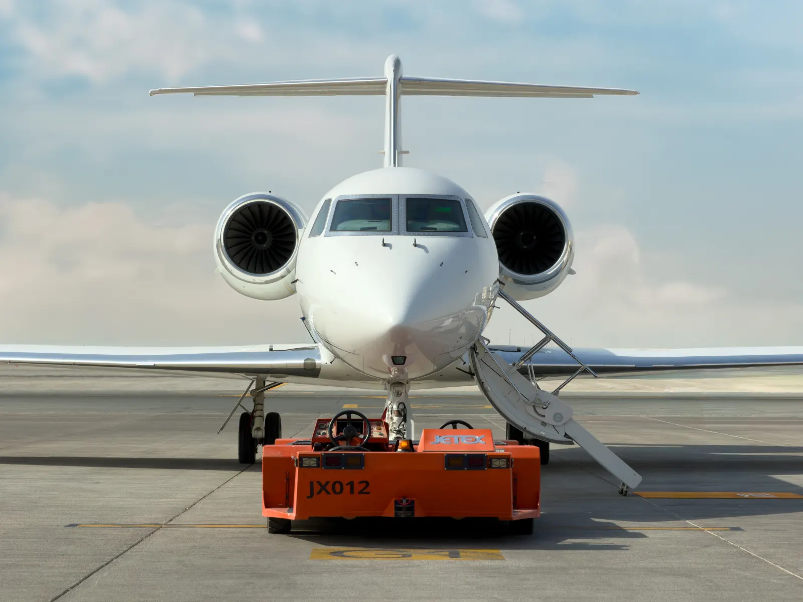 Gulfstream G450 nose-on at Dubai World Central with its airstair down and a tug coupled at the nose gear