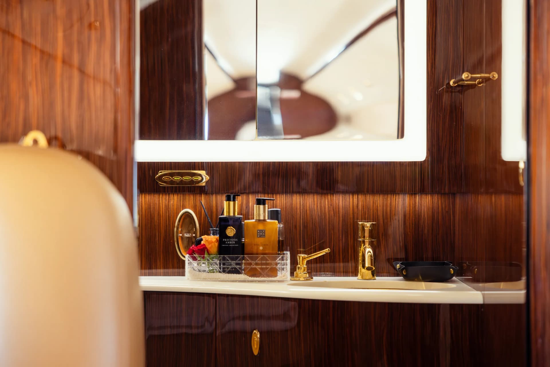 The Gulfstream G200 lavatory with a wood-panelled vanity, mirror and gold fittings