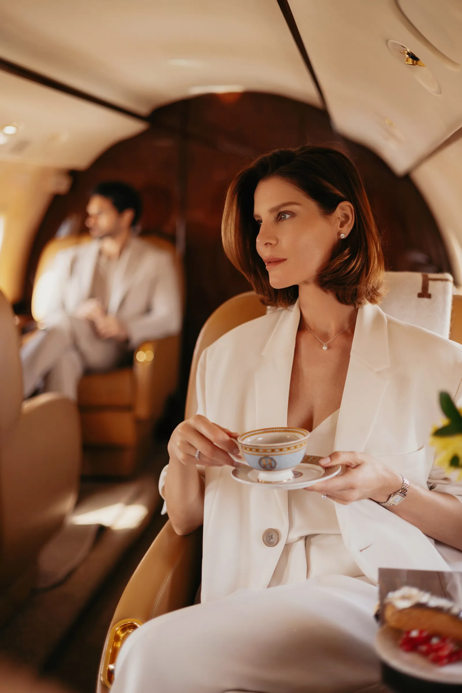 A guest with a cup of tea in the cabin, another passenger relaxing behind her