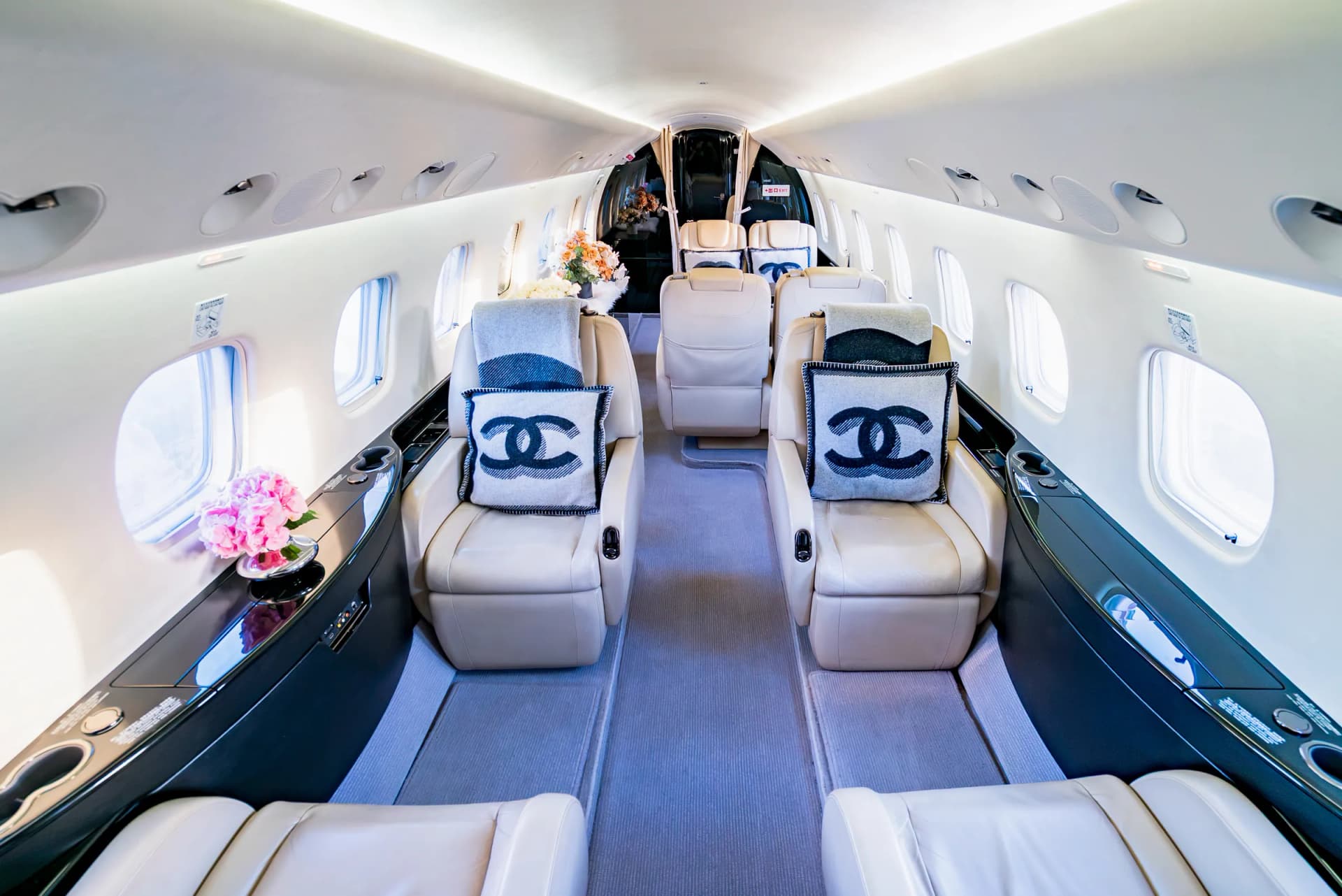 The Embraer Legacy 650 cabin aisle between cream seats with Chanel cushions