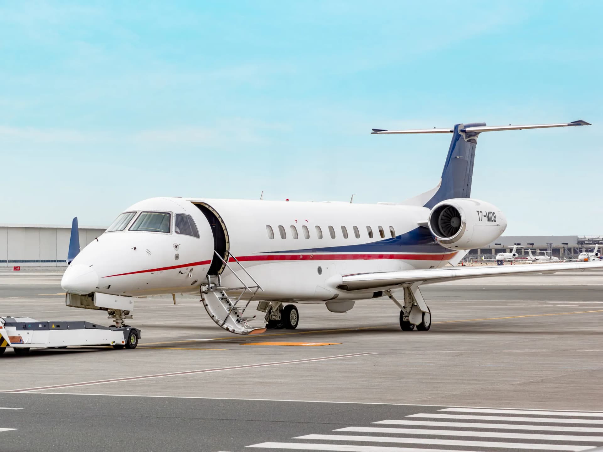 Embraer Legacy 650 T7-MIDB on the ramp with its airstair down and a tug at the nose