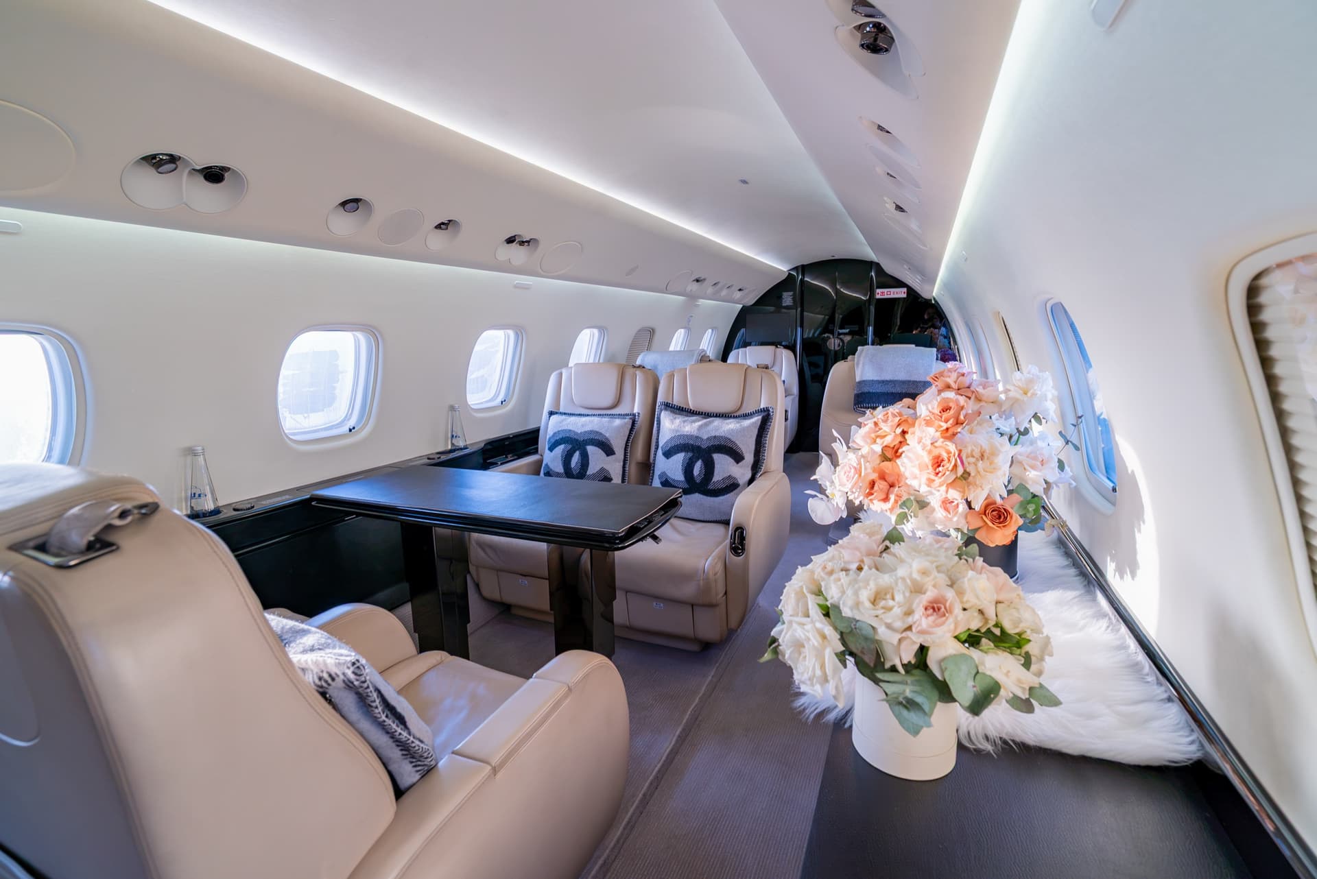 Embraer Legacy 650 club seating with a conference table and floral arrangements along the credenza